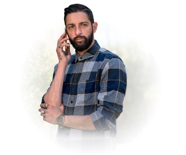 Un hombre con barba al teléfono está girado ligeramente hacia la derecha.